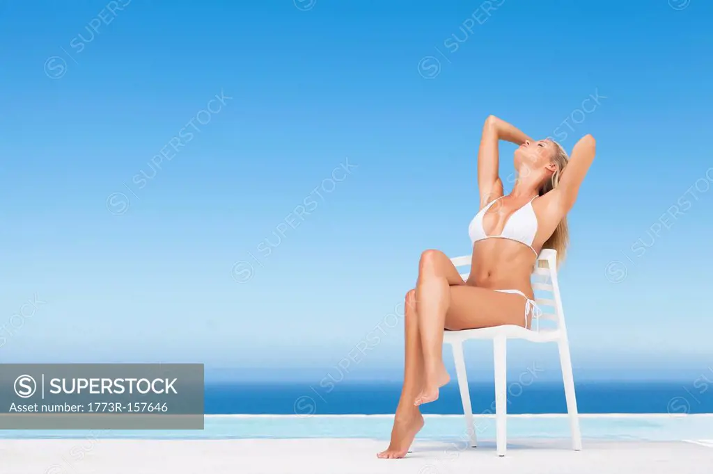 Woman relaxing in lawn chair by pool