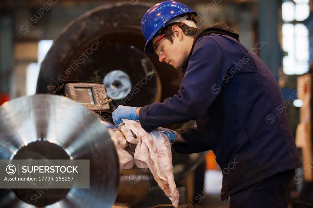 Worker cleaning metal in steel forge