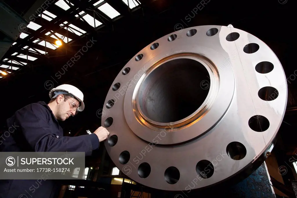 Worker examining metal in steel forge