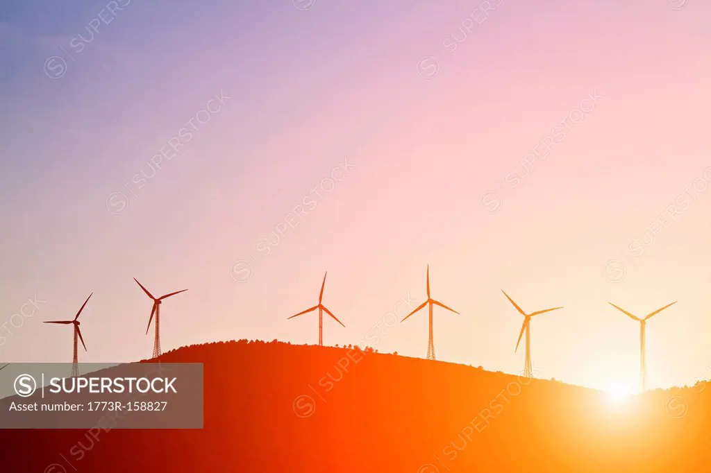 Silhouette of windmills on rural hills