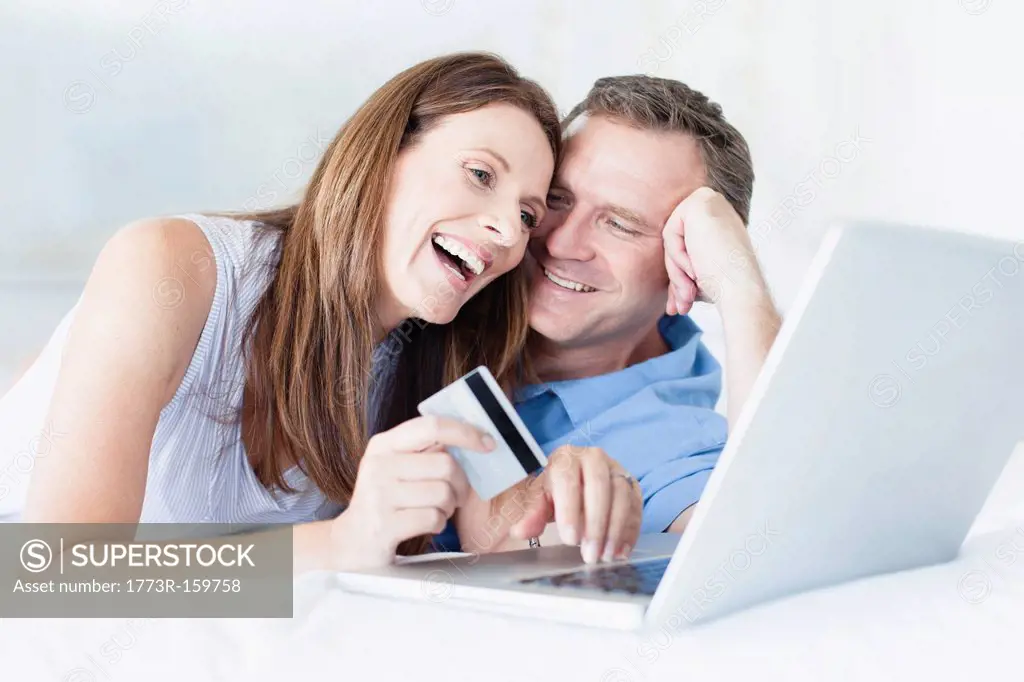 Couple shopping online on bed