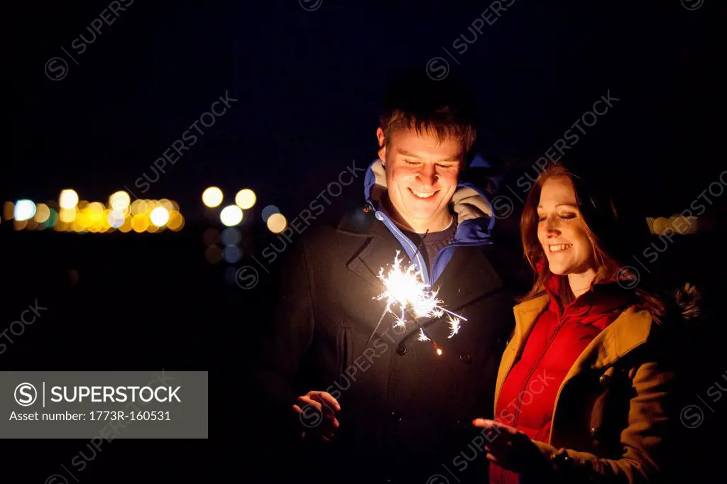 Smiling couple playing with sparklers