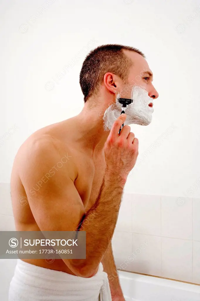Man shaving face in bathroom
