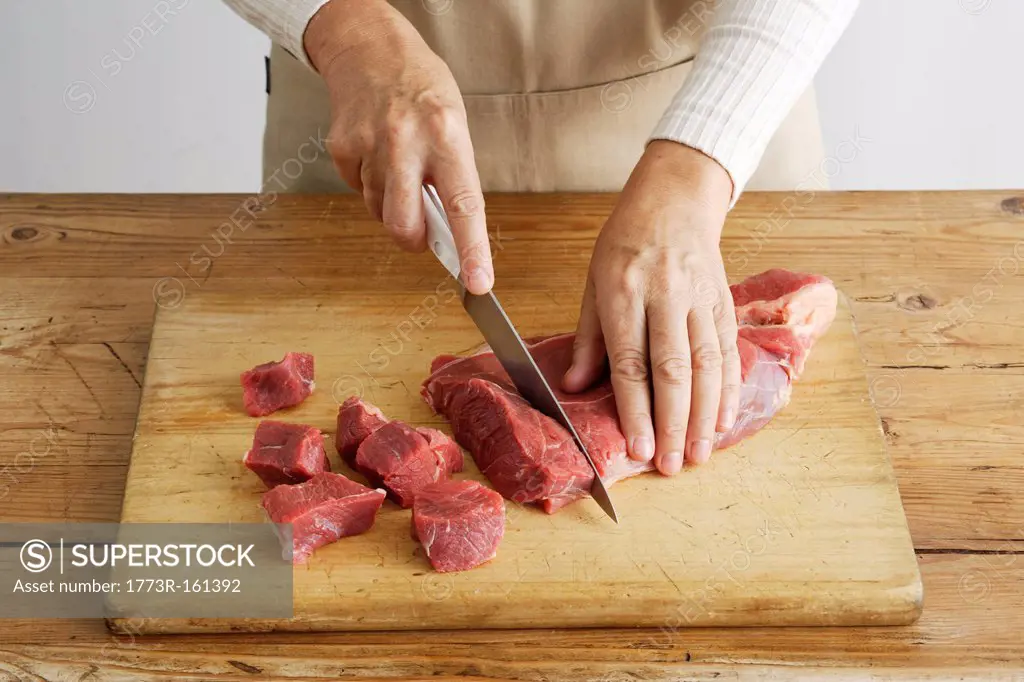 Woman slicing meat on wooden board