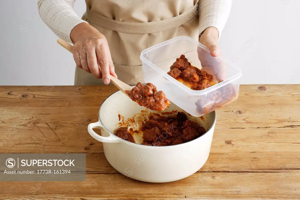 Woman spooning meat into tupperware