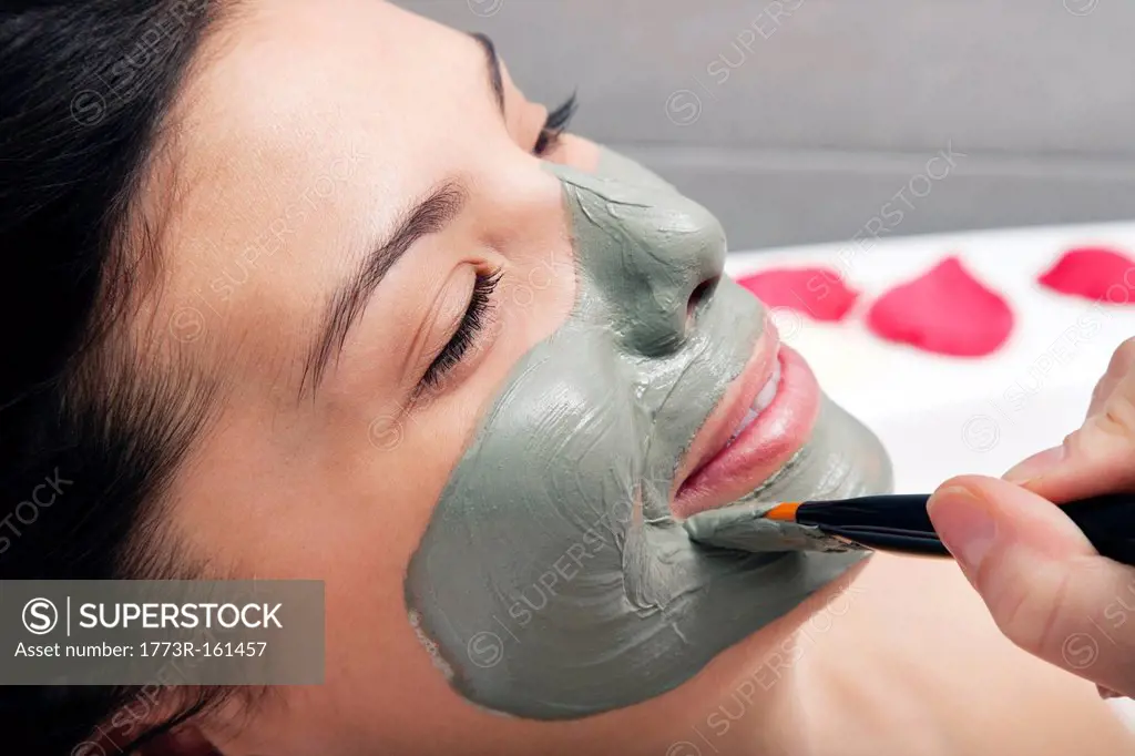 Woman having skin mask applied in bath