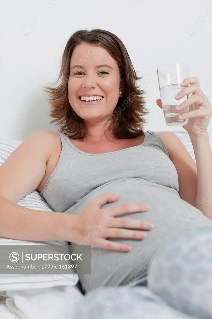 Woman holding pregnant belly on bed