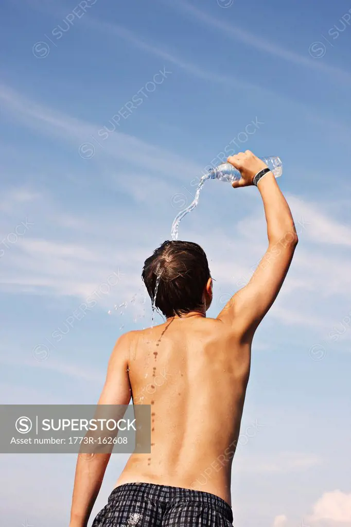 Teenage boy pouring water on himself