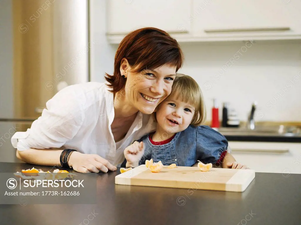 Mother and daughter peeling orange