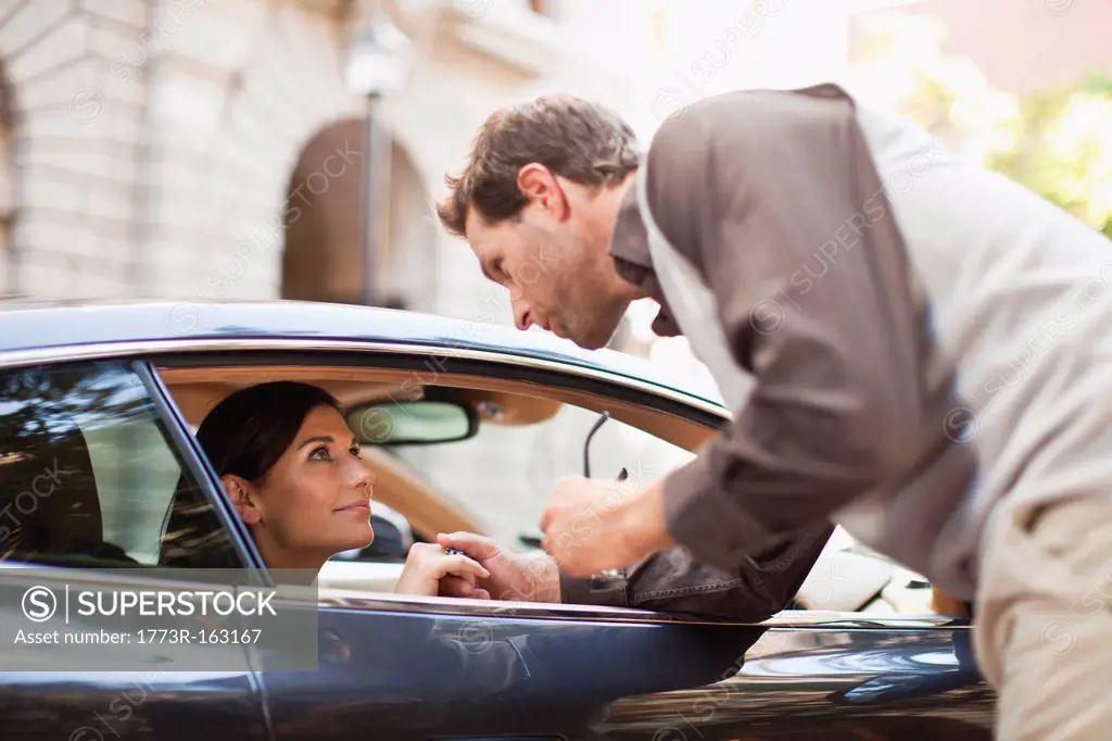 Man talking to woman through car window