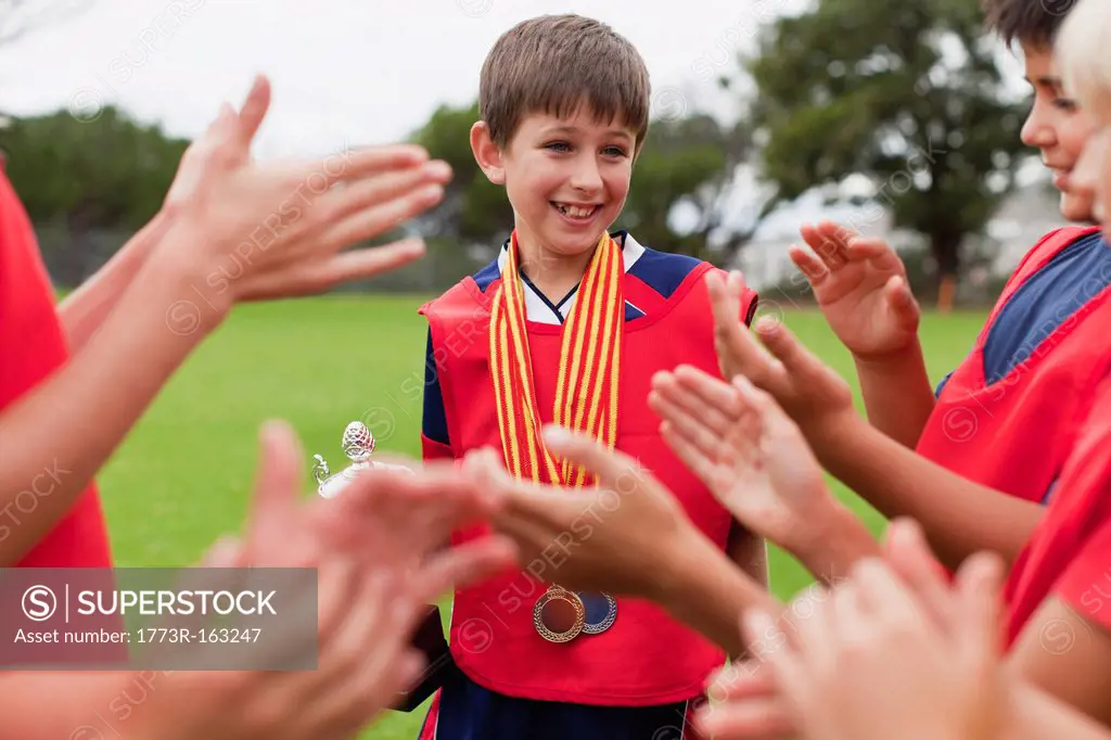 Children cheering teammate with trophy