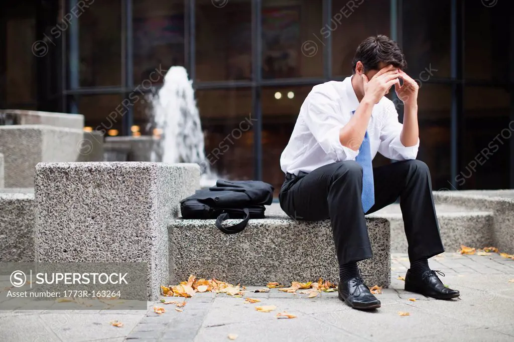 Businessman sitting on urban fountain