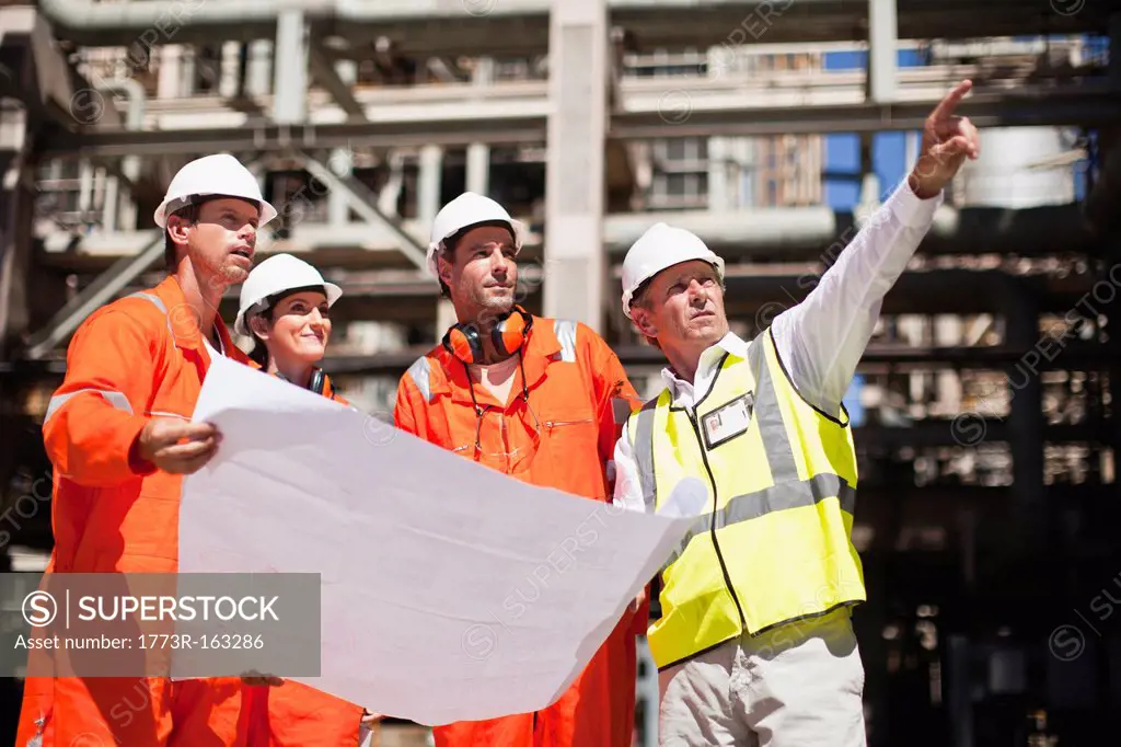 Workers with blueprints at oil refinery