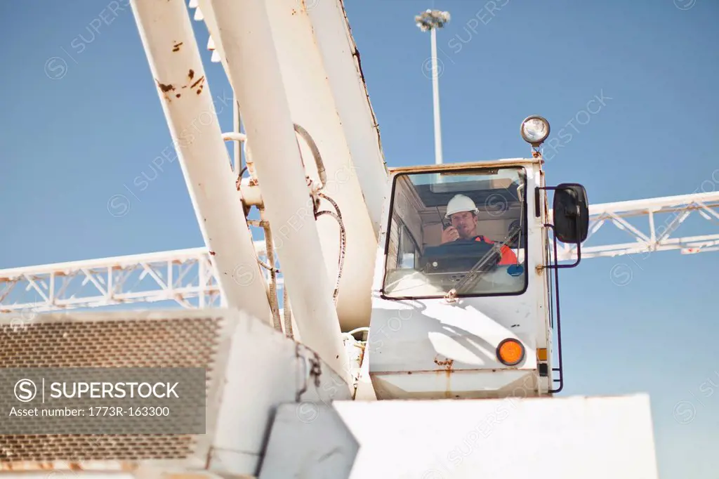 Worker operating crane at oil refinery