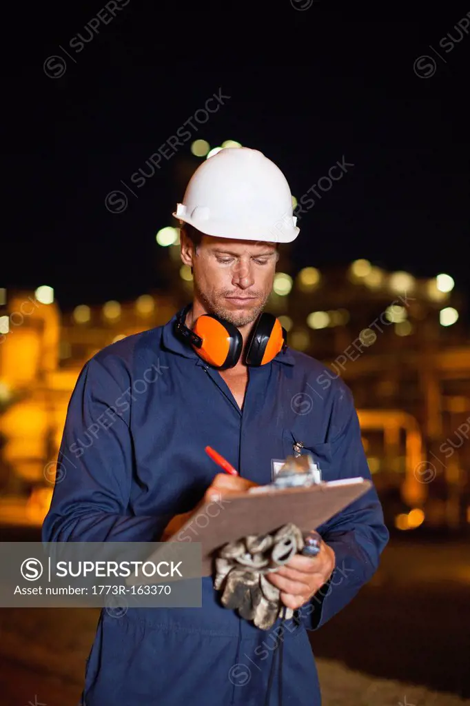 Worker with clipboard at oil refinery