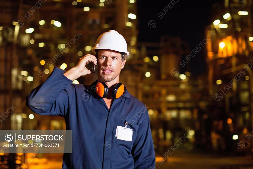 Worker on cell phone at oil refinery