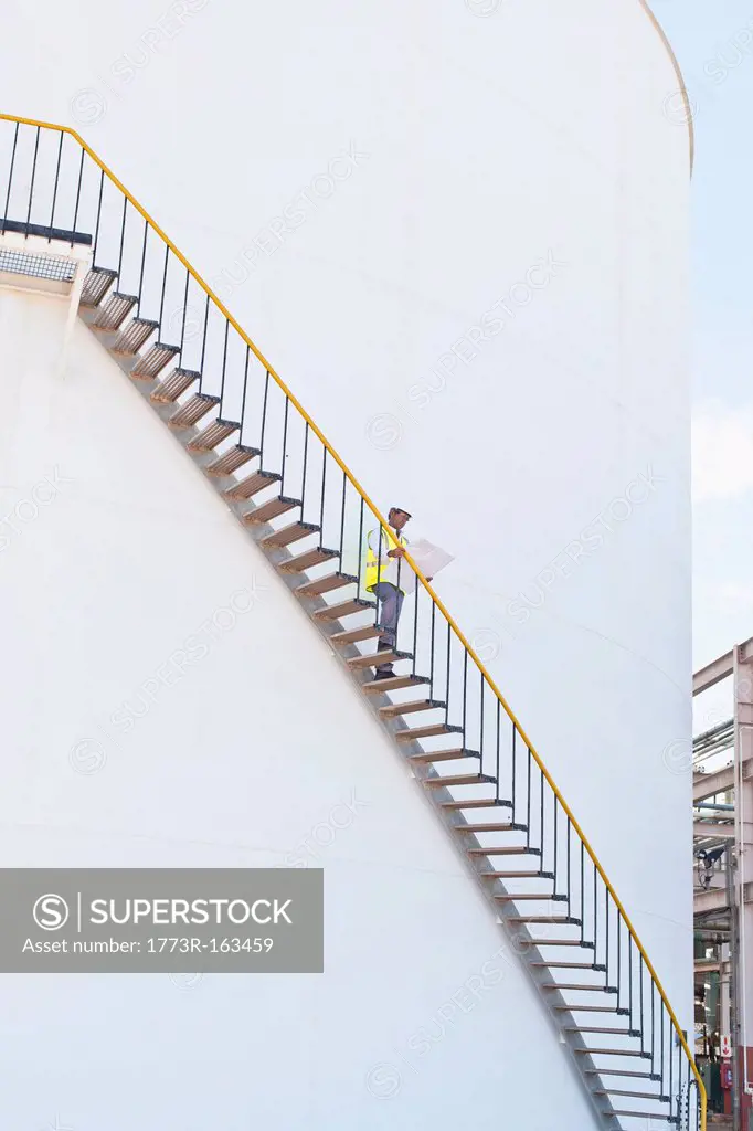 Worker climbing steps at chemical plant