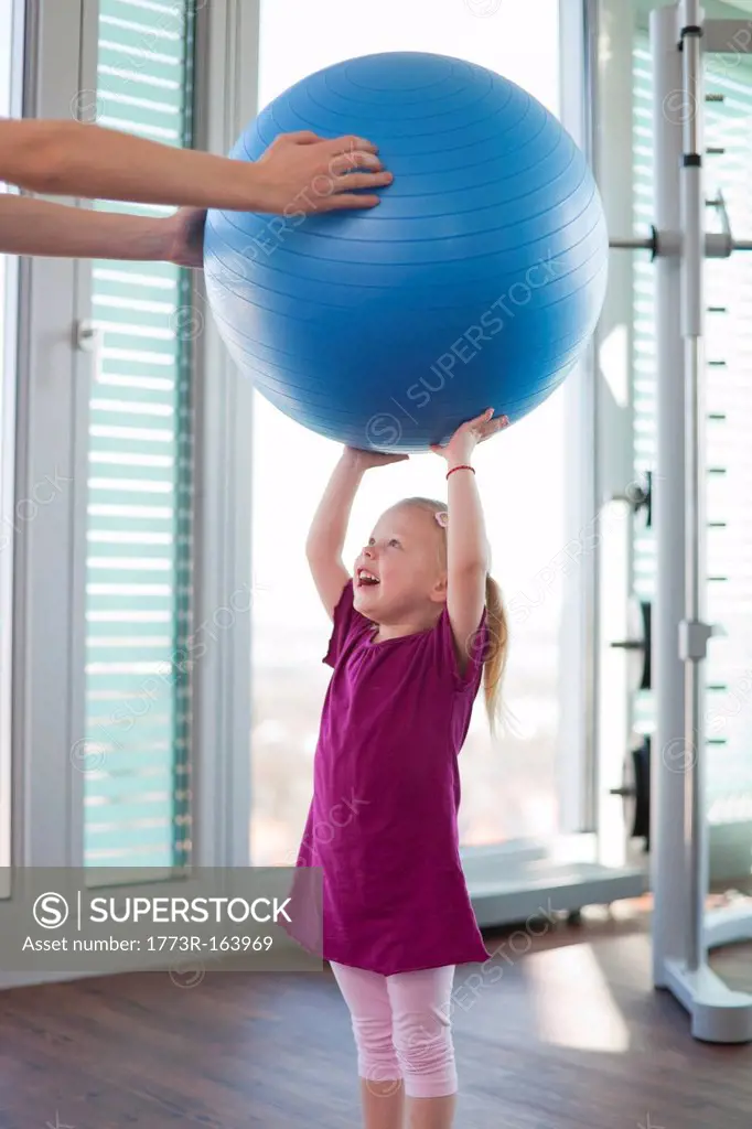 Girl playing with exercise ball in gym
