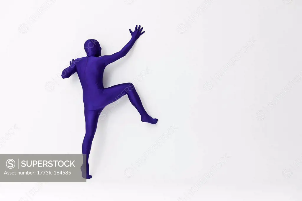 Man in bodysuit scaling wall