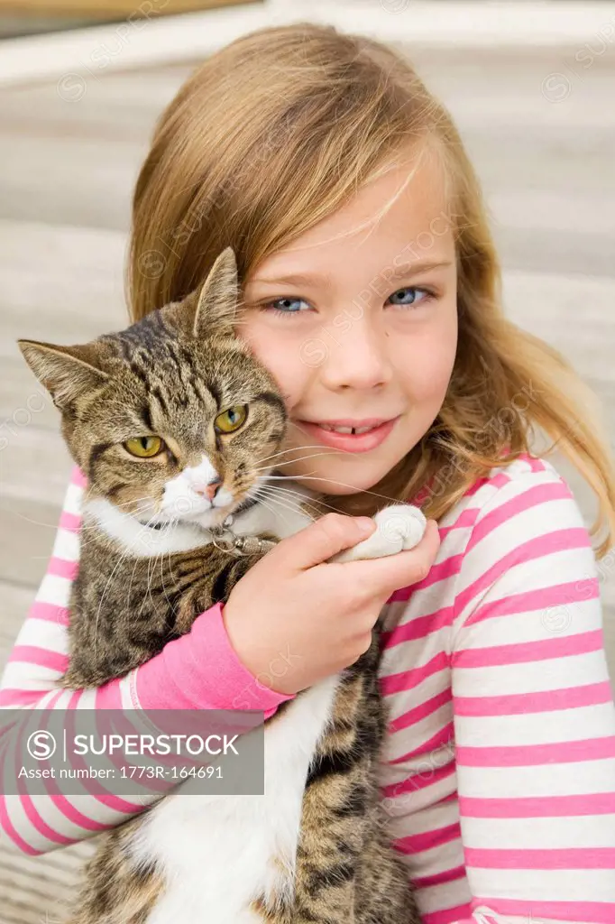 Smiling girl holding cat outdoors