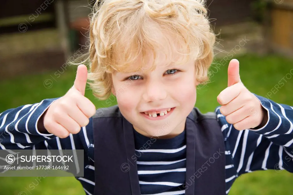 Smiling boy giving thumbs_up outdoors