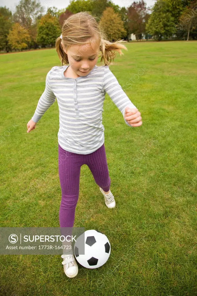 Girl playing with soccer ball in field