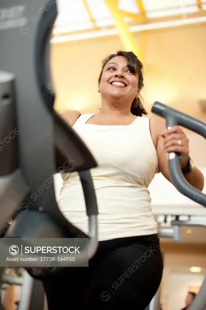 Woman using elliptical machine in gym