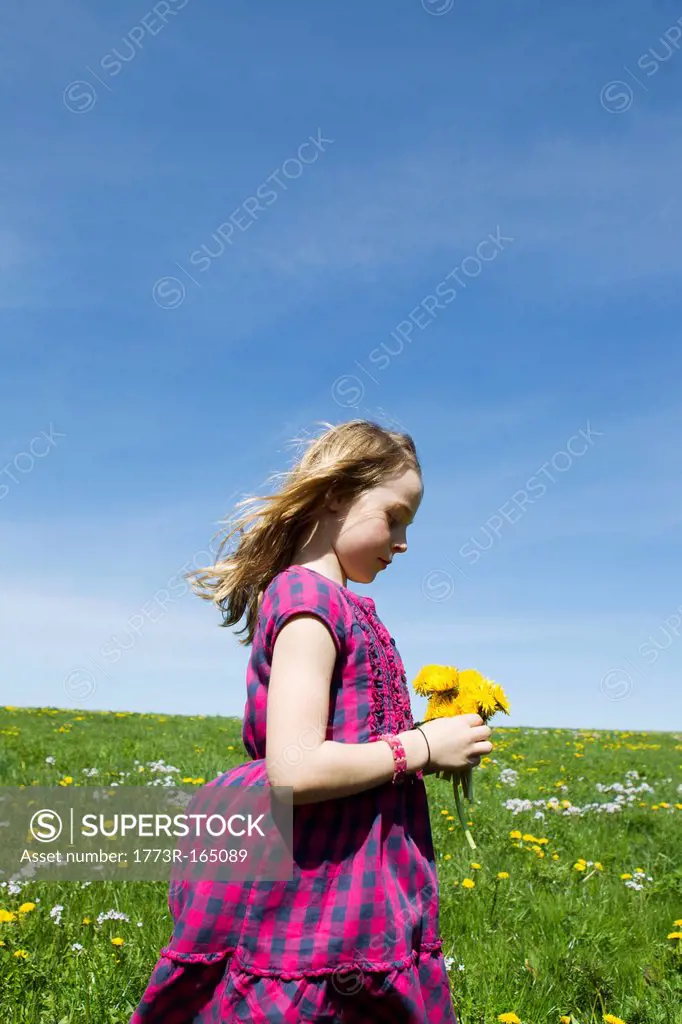 Girl carrying wildflowers in field