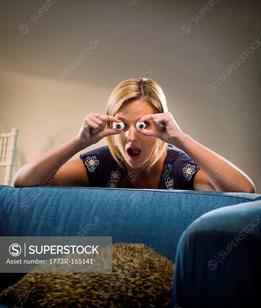 Woman holding glass eyes in living room