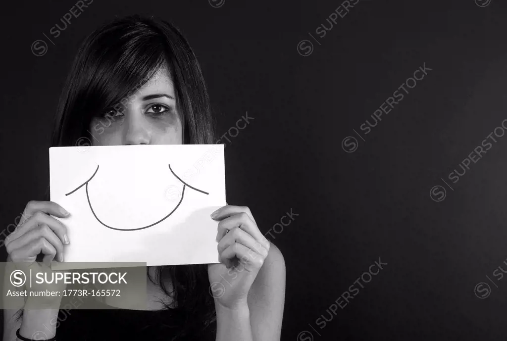Crying teenage girl holding fake smile