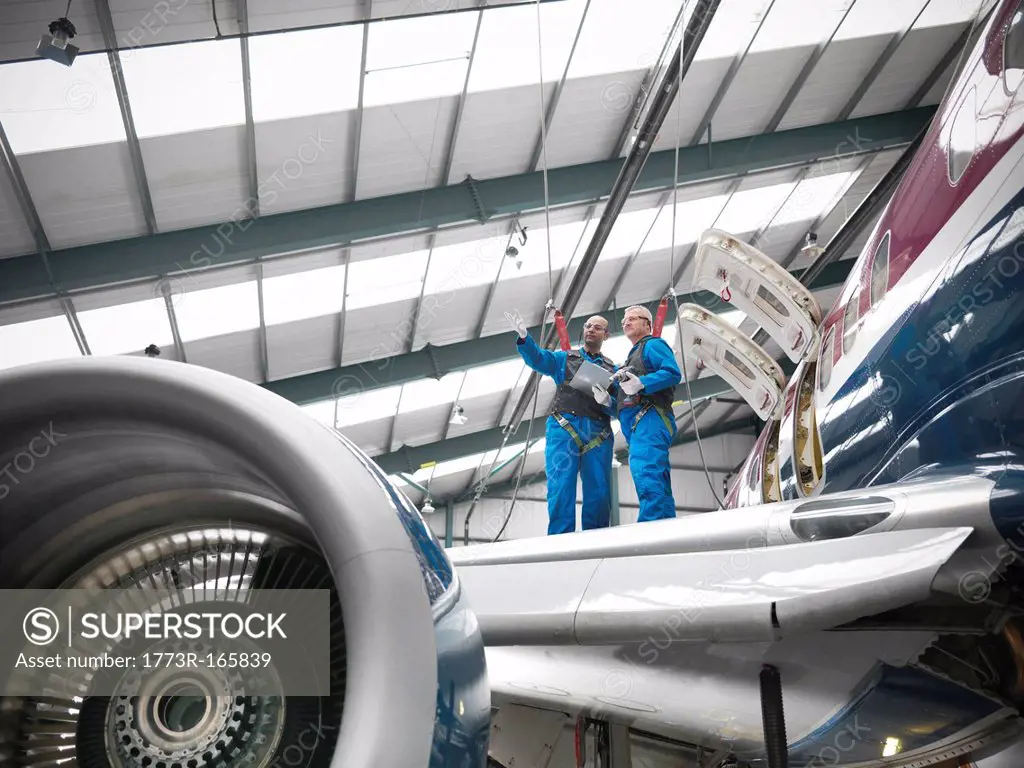 Workers examining airplane in hangar