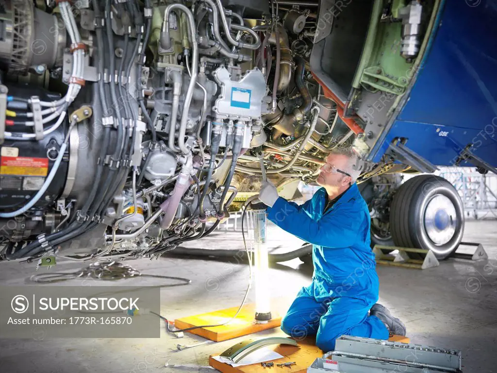 Worker examining airplane machinery