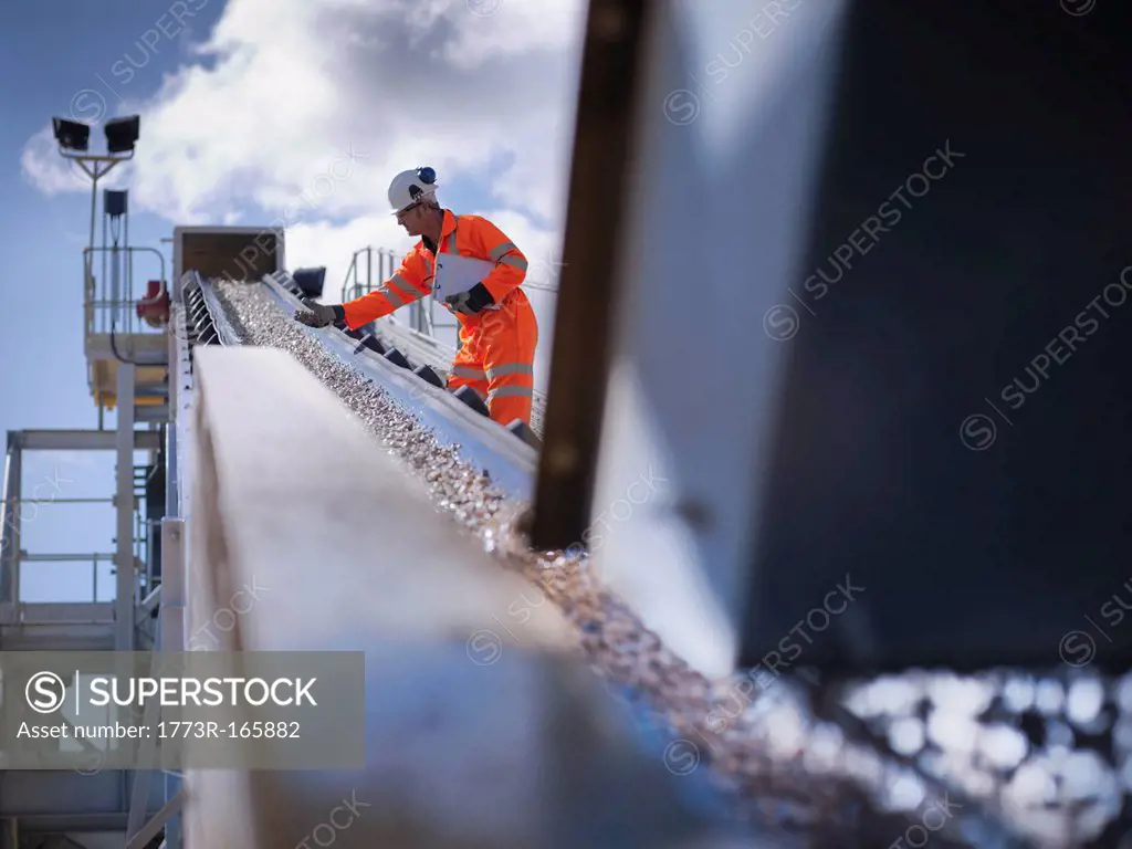 Worker examining stones on conveyor belt