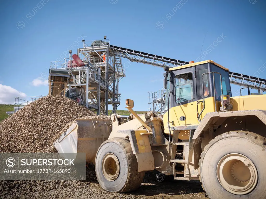 Digger scooping pile of stones in quarry