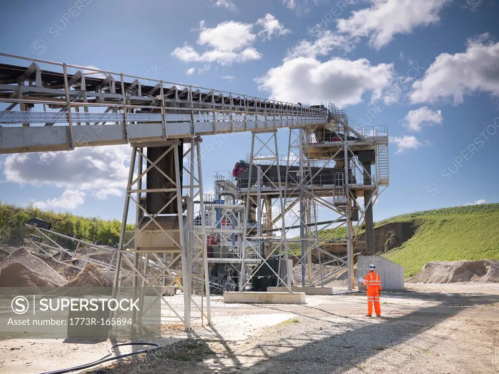 Worker standing by conveyor in quarry