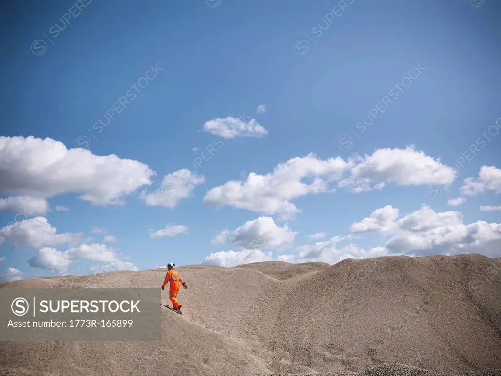 Worker climbing sand dunes in quarry