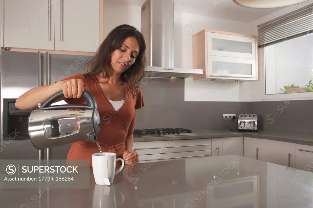 Woman making cup of tea in kitchen