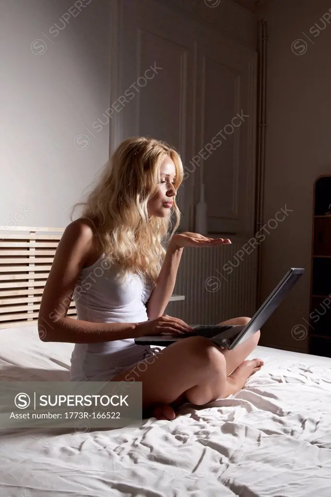 Woman using webcam on bed