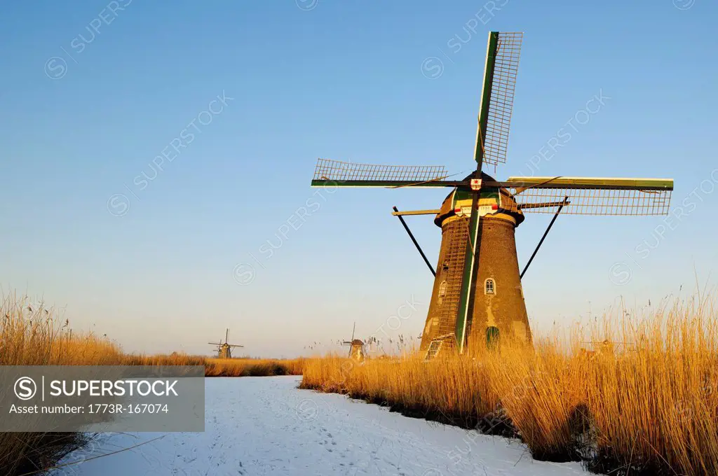 Windmill by river in rural landscape