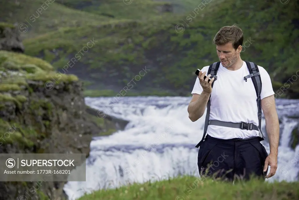 Hiker using cell phone on hillside