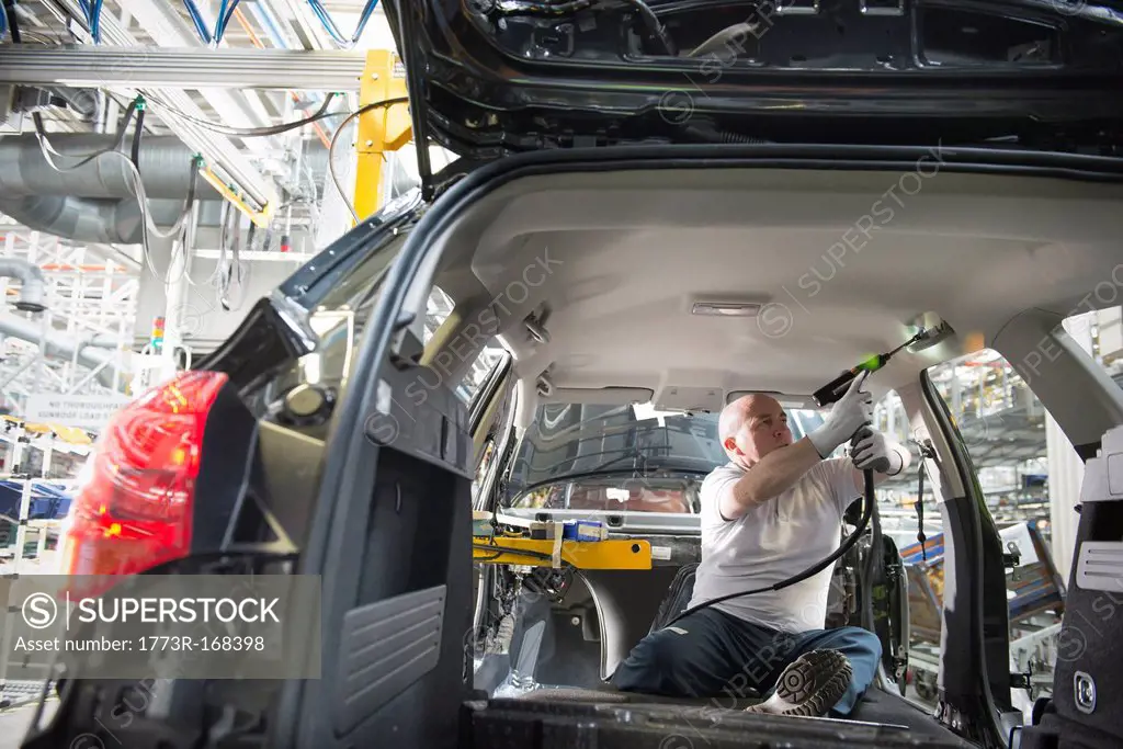 Worker fitting headliner in car in car factory