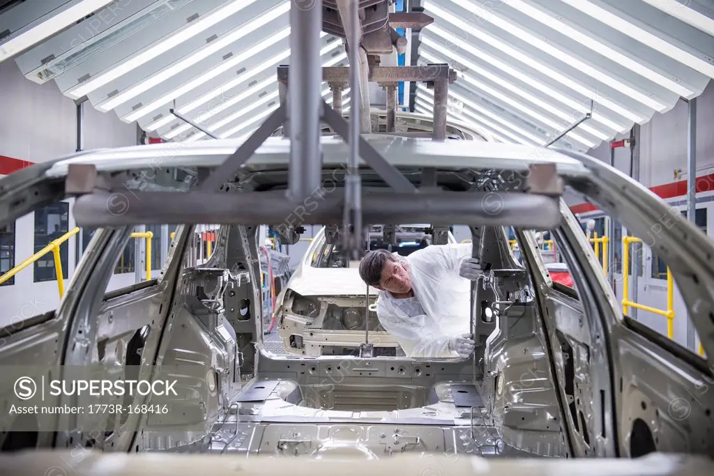Worker inspecting car body in car factory