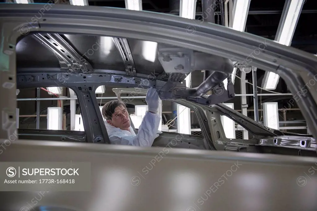 Worker inspecting car body in car factory