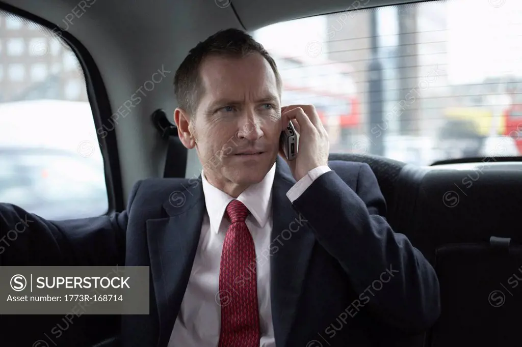 Businessman on cell phone in backseat