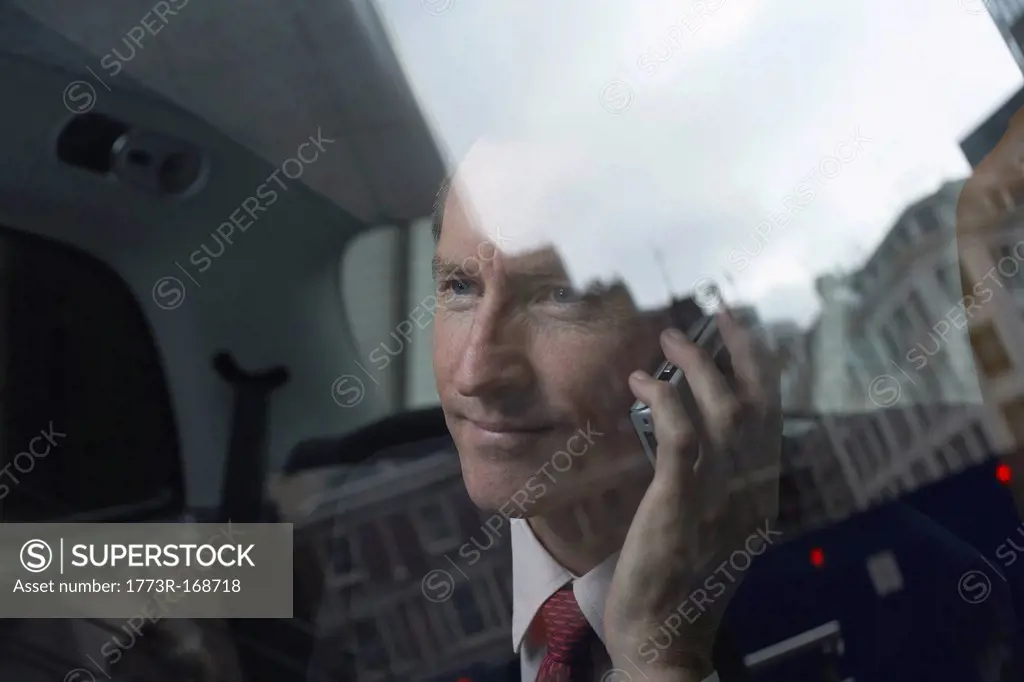 Businessman on cell phone in backseat