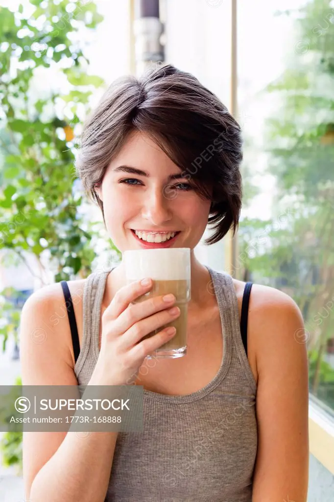 Smiling woman drinking coffee outdoors