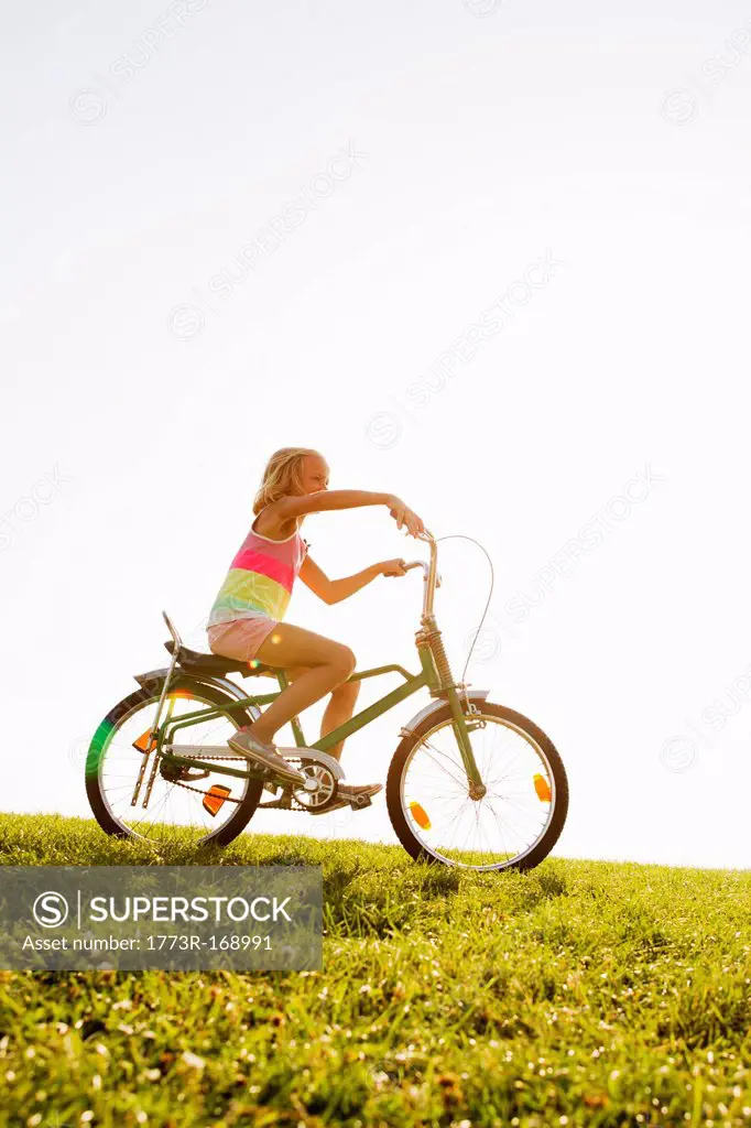 Girl riding bicycle in grass