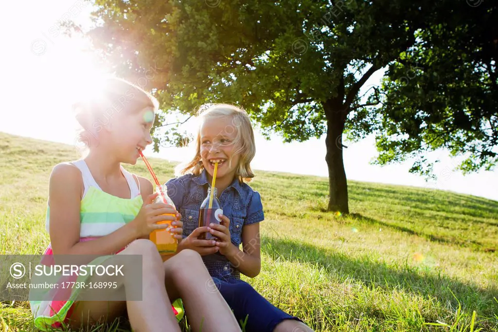 Laughing girls drinking juice outdoors