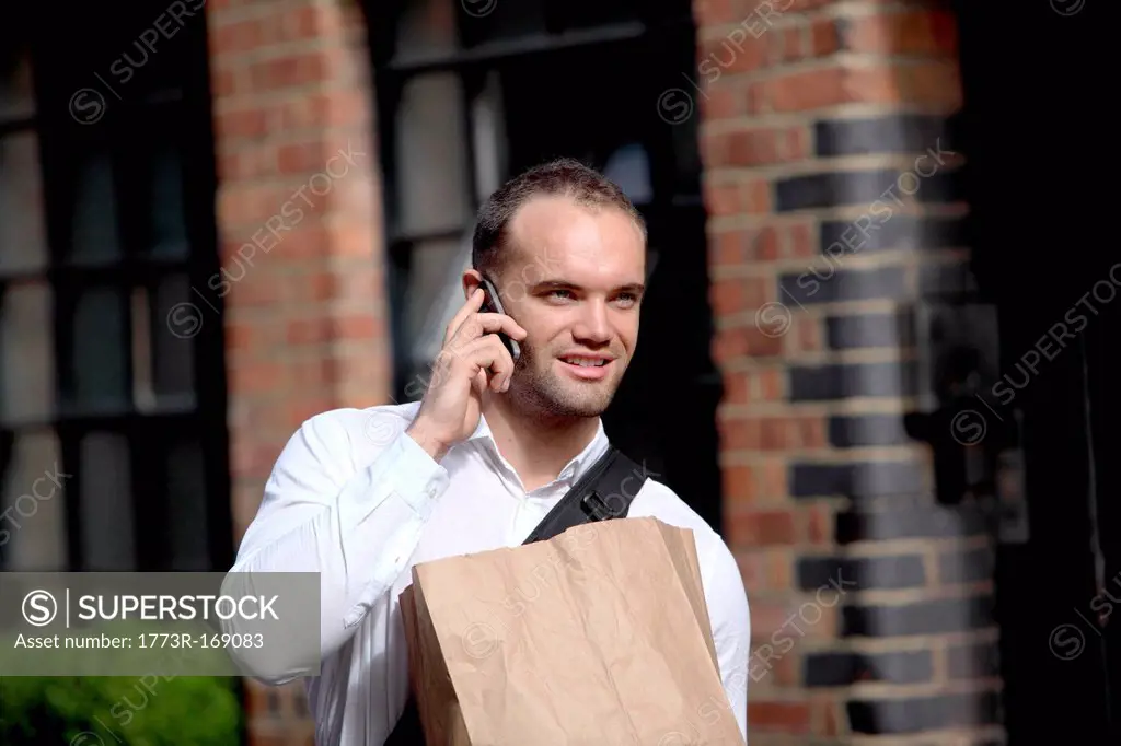 Businessman on cell phone on city street