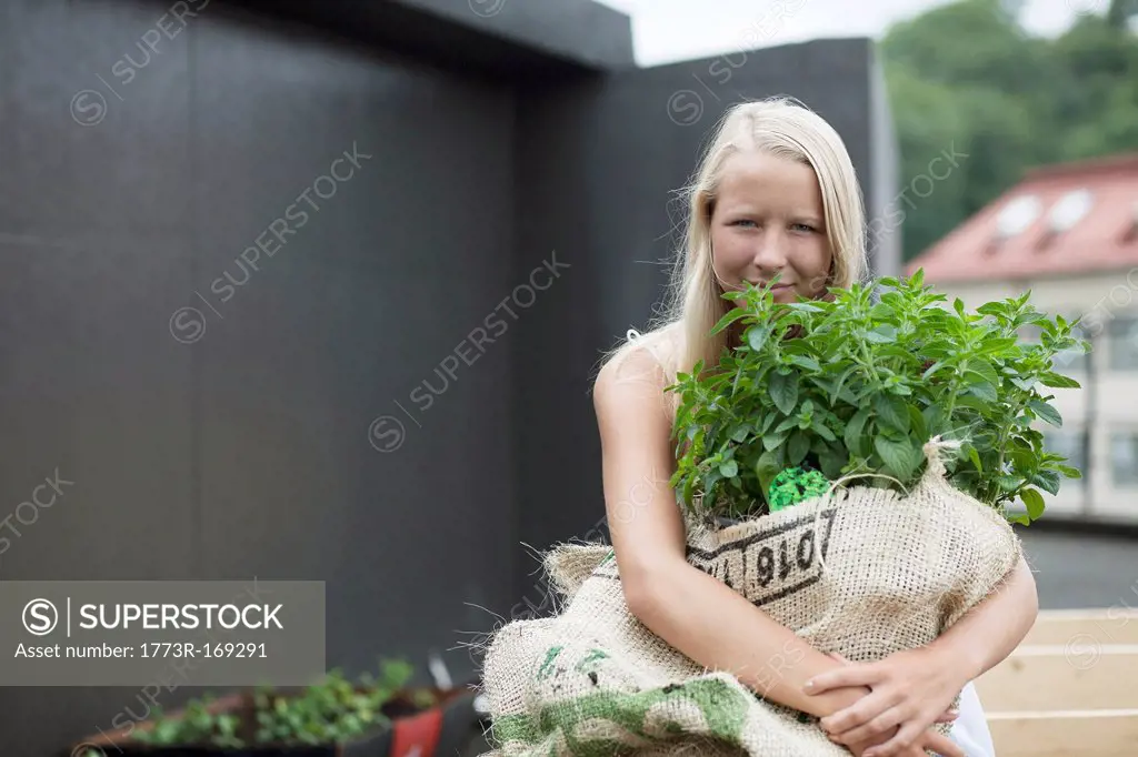 Teenage girl holding sack of plants